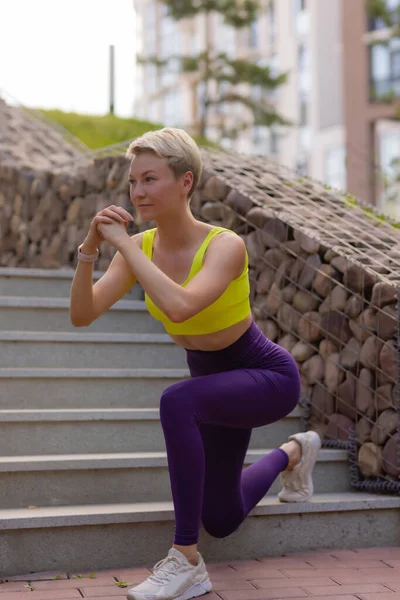 En ung kvinna förbereder sig för utomhussporter på den moderna promenaden nära sin lägenhetskomplex. — Stockfoto