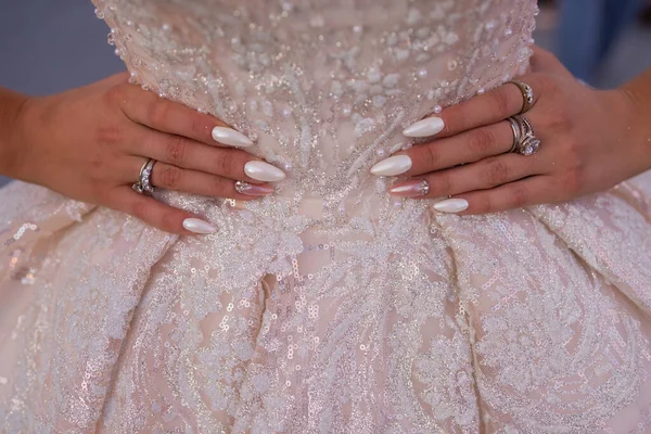 Платье невесты крупным планом с красиво вышитым узором и руками на талии с красивым маникюром. — стоковое фото