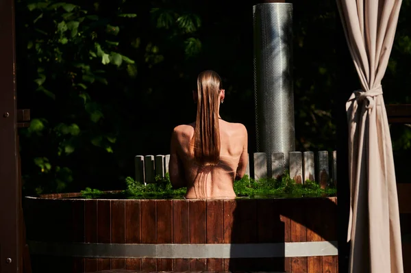 Pijnboomtakken in de buurt van een warme conifer in een water van hete buis spa. — Stockfoto