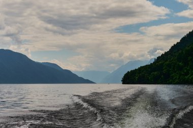 Tekne, Teletskoye Gölü, Altai Cumhuriyeti, Rusya 'nın göl suyunun yüzeyini kesiyor..