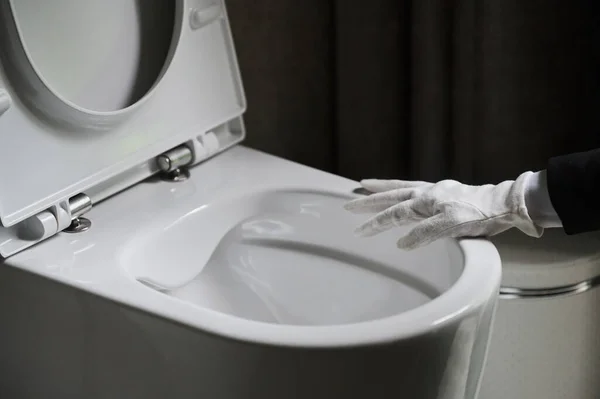Huishoudster in een nette witte schort staan schrobben van een toilet met een borstel. — Stockfoto