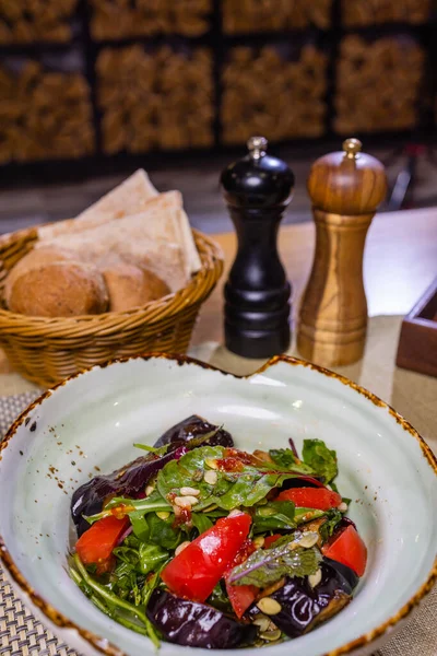 Gegrillte Auberginen mit frischen und getrockneten Tomaten, Rucola und Nüssen. — Stockfoto