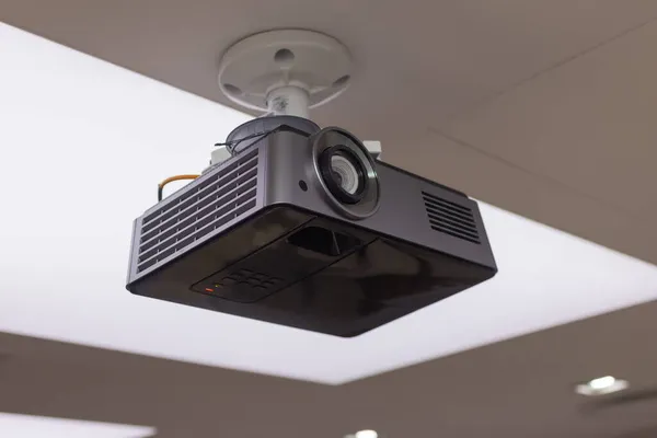 Um projetor aéreo preto no teto em uma sala de conferências moderna sala de aula cor tonificada imagem. — Fotografia de Stock