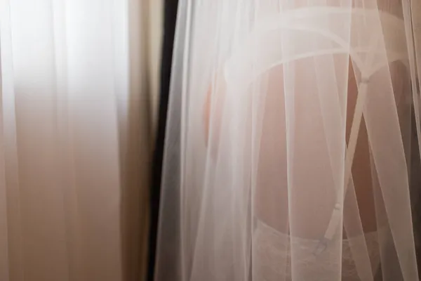 Novia irreconocible en una túnica de seda con hermosas piernas delgadas se está poniendo medias. Preparación de la boda mañana. Ropa interior de vestir, tocador . — Foto de Stock