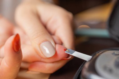 Kadın yüksek kan şekeri testi yapıyor. Kan şekerini ölçmek için kadın tutucu.