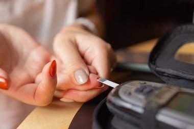 Kadın yüksek kan şekeri testi yapıyor. Kan şekerini ölçmek için kadın tutucu.