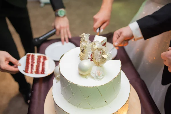 Руки жениха и невесты, вырезанные из куска свадебного торта. — стоковое фото