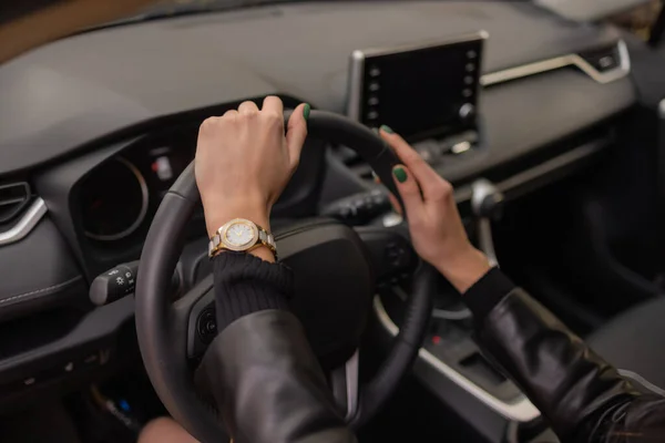Mulheres mãos segurando a roda de um carro novo no showroom. — Fotografia de Stock