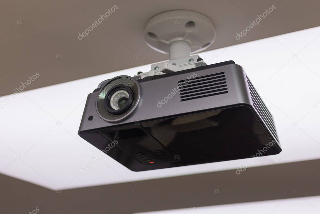 A black overhead projector on ceiling in a conference room modern classroom color toned image.