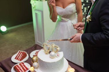 Gelin ve damadın elleri bir dilim düğün pastasından kesilmiş..