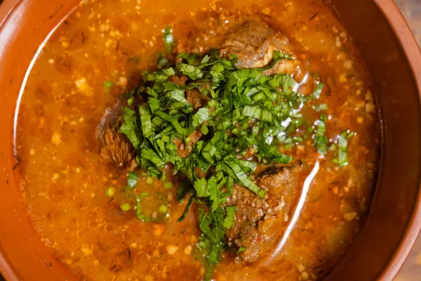 A bowl of beef vegetable soup garnished with dill and parsley. — Stock Photo, Image