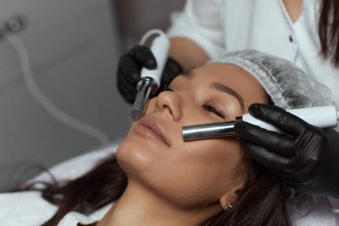 Kozmetoloji. Spa Kliniğinde Güzel Kadın Terapistten Elektriksel Yüz Tedavisi Alınıyor.