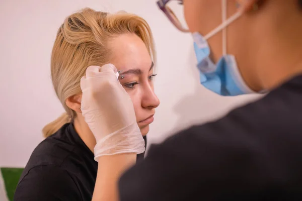 Professional placing the jewel of piercing on the temple on the head with ball. Tragus type. — Stock Photo, Image