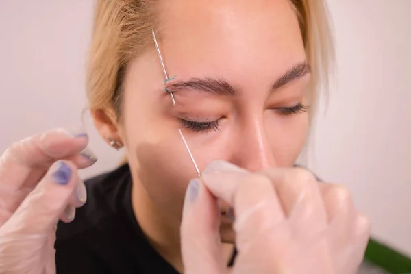 Professional placing the jewel of piercing on the temple on the head with ball. Tragus type. — Stock Photo, Image