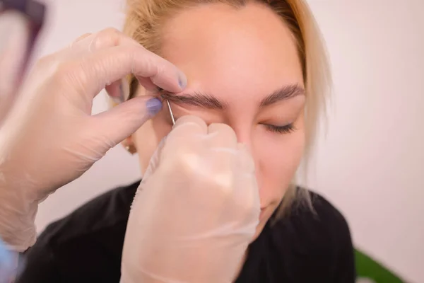 Professionale posizionando il gioiello di piercing sulla tempia sulla testa con palla. Tipo tragus. — Foto Stock