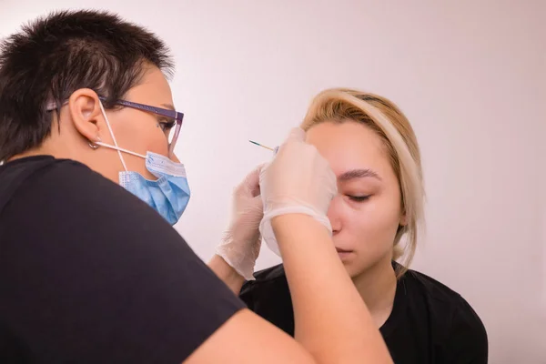 Professional placing the jewel of piercing on the temple on the head with ball. Tragus type. — Stock Photo, Image