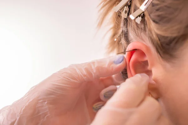 Professional placing the jewel of piercing on the ear with ball. Tragus type. — Stock Photo, Image