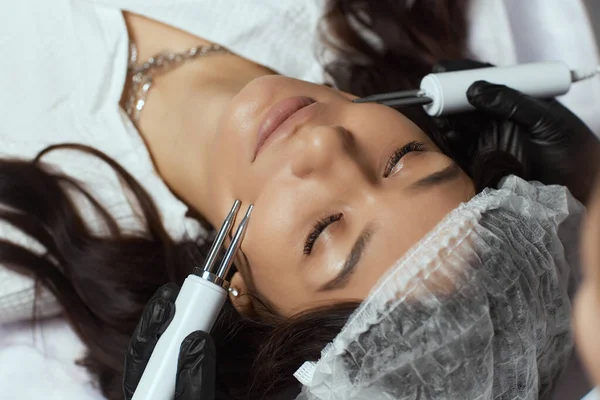 Kosmetologie. schöne Frau in der Kurklinik erhält stimulierende elektrische Gesichtsbehandlung vom Therapeuten. — Stockfoto