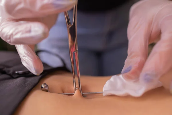 Il primo piercing. Vestire gli orecchini sull'ombelico. Piercing femminile . — Foto Stock