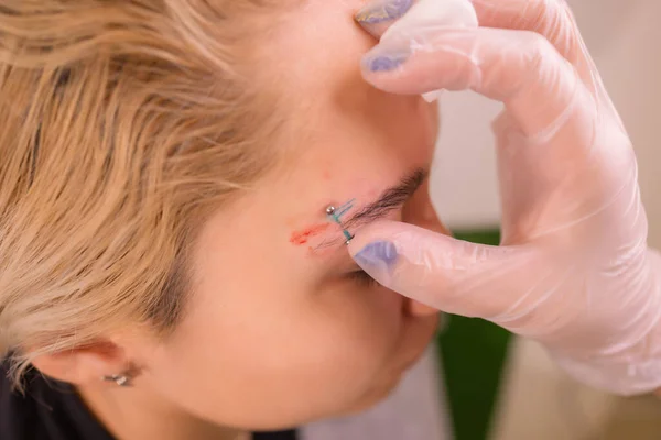 Professional placing the jewel of piercing on the temple on the head with ball. Tragus type. — Stock Photo, Image