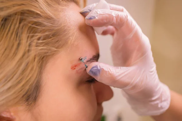Professional placing the jewel of piercing on the temple on the head with ball. Tragus type. — Stock Photo, Image
