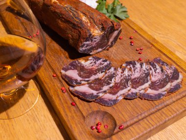 Ahşap bir masada dilimlenmiş tütsülenmiş tavla taze otlar ve aromatik baharatlar ilave edilir..