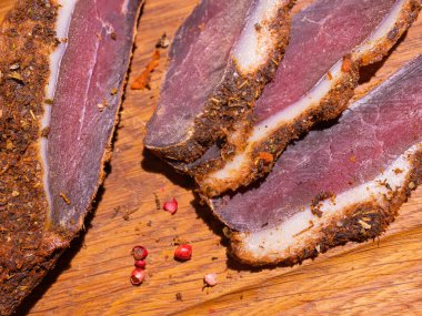 Ahşap bir masada dilimlenmiş tütsülenmiş tavla taze otlar ve aromatik baharatlar ilave edilir..