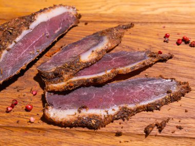 Ahşap bir masada dilimlenmiş tütsülenmiş tavla taze otlar ve aromatik baharatlar ilave edilir..