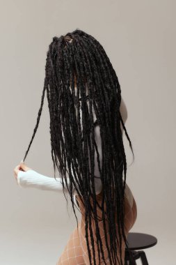 Beyaz arka planda siyah afrokolar olan genç bir kadın..