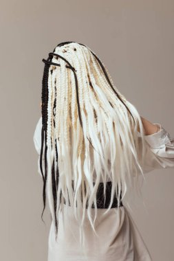 Beyaz arka planda siyah afrokolar olan genç bir kadın..