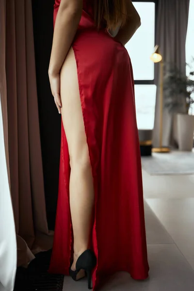 Довгі ноги дівчини в бежевому відкритому взутті з шипами і в червоній довгій сукні . — стокове фото