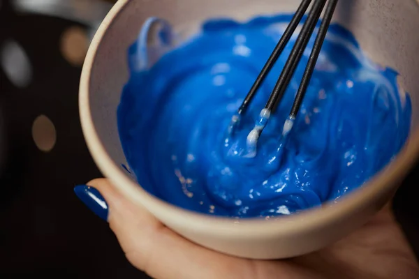 Girl in white rubber protective gloves holding a brush in her hands and stirring hair dye close-up colorist. — Stock Photo, Image