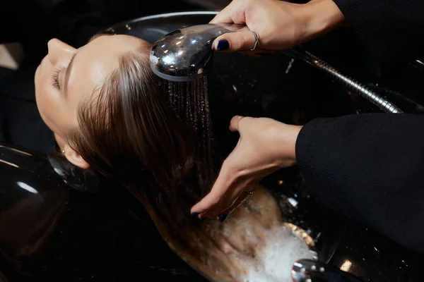 Peluquería en el salón de belleza lava el cabello de su cliente, antes del procedimiento de aplicación de ingredientes naturales de restauración y vitaminas para el cabello y corte de pelo. — Foto de Stock