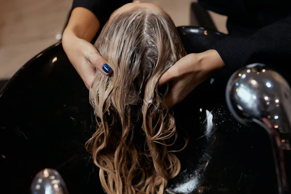 Перукар в салоні краси миє волосся клієнта, перед процедурою нанесення натуральних інгредієнтів і вітамінів для волосся і стрижки . — стокове фото