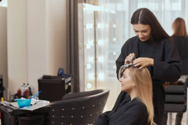 Saç stilisti ince tellerde tarak kullanarak kabarık yapar. Saç şimşeği için Shatush tekniği.