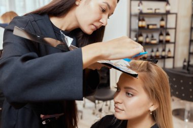 Saç stilisti ince tellerde tarak kullanarak kabarık yapar. Saç şimşeği için Shatush tekniği.