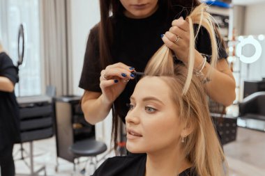 Saç stilisti ince tellerde tarak kullanarak kabarık yapar. Saç şimşeği için Shatush tekniği.