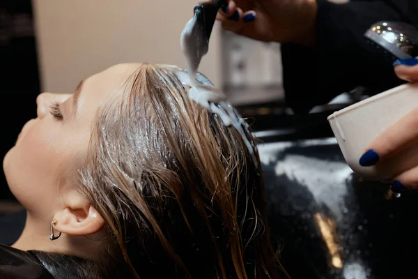 Fryzjer w salonie kosmetycznym myje włosy swojego klienta, przed zabiegiem stosowania naturalnych składników przywracających i witamin do włosów i fryzury. — Zdjęcie stockowe