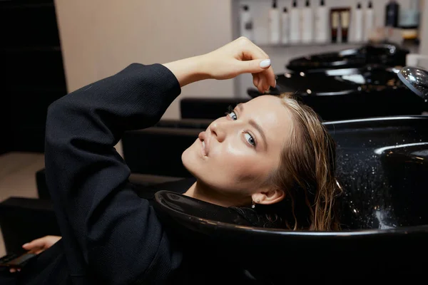 미용실에 있는 헤어 드레서는 머리와 머리를 깎는데 천연물 과 비타민을 사용하기 전에 고객의 머리를 씻는다. — 스톡 사진