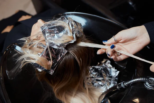 Cabeleireiro no salão de beleza lava seu cabelo cliente, antes do procedimento de aplicação de ingredientes naturais restauradores e vitaminas para o cabelo e corte de cabelo. — Fotografia de Stock