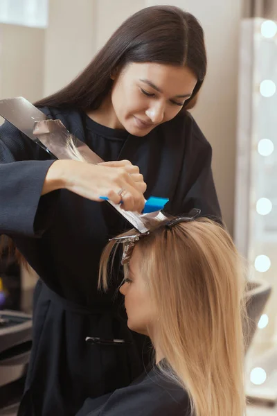 Hårstylist gör bouffant med hjälp av kam på tunna trådar. Shatush teknik för hår ljusare. — Stockfoto