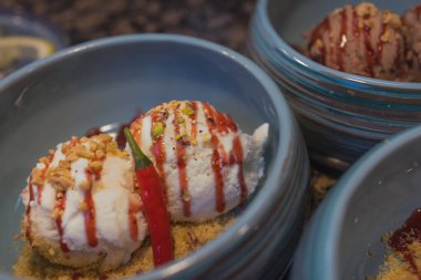 Vanilyalı dondurma ve çikolata. Krem şanti, kırmızı jöle, nane yaprağı ve çikolata şurubuyla süslenmiş iki katmanlı. Tabağa portakallı dondurma konmuş..