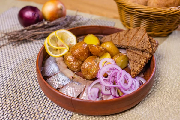 De la nourriture. Hareng aux oignons et pommes de terre sur une assiette en pierre noire. — Photo