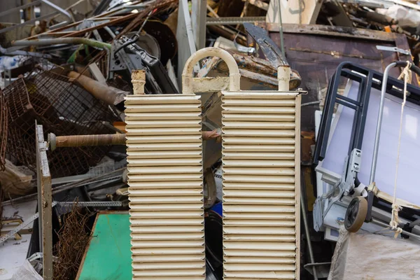 Multi colored cast iron radiators, old heating elements stacked in heap. Old batteries made of cast iron lying on the ground. — Fotografia de Stock