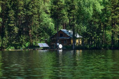 Gölün yanında kayalık bir ev ve önünde güzel bir doğal ortamda küçük bir tekne olan peri masalı manzarasının nefes kesici ve renkli manzarası. Şaşırtıcı doğa duvar kağıdı arkaplanı.