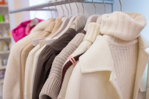 Suéteres cálidos de punto pastel en perchas blancas. —  Fotos de Stock