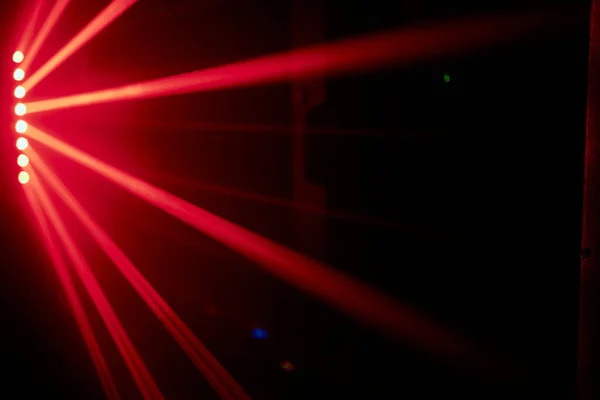 Parlak kırmızı neon lazer ışıkları karanlığı aydınlatır. Bilim kurgu efektiyle çizgiler ve üçgen şekiller yaratır.. — Stok fotoğraf