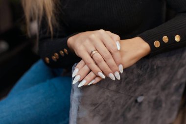 Güzel manikür. Tırnak cilası elde kullanılıyor. Cila mavi bir renktir. Mavi arkaplan yakın plan.