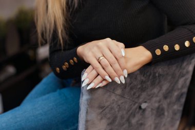 Güzel manikür. Tırnak cilası elde kullanılıyor. Cila mavi bir renktir. Mavi arkaplan yakın plan.