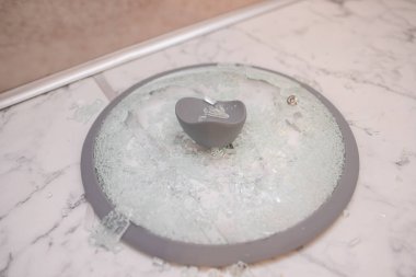 Kırık bir cam kapağın yakın çekimi bir fayans kazığının üzerinde yatıyor. Cam kırıkları parlıyor. yumuşak odak, üst görünüm.